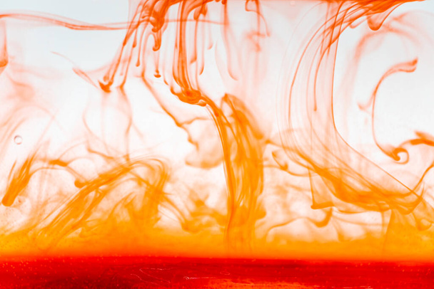 Nahaufnahme rote Farbe Tinte Flüssigkeit und Rauch Abstrakter Hintergrund. Farbtropfen fließen im Wasser. - Foto, Bild