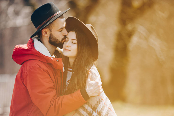 01.06.2019 Vinnitsa, Ukraine: portrait of a stylish wedding couple: Young bearded man in hat and brunette bride in elegant gown wearing a wreath braided in hairstyle - Foto, afbeelding