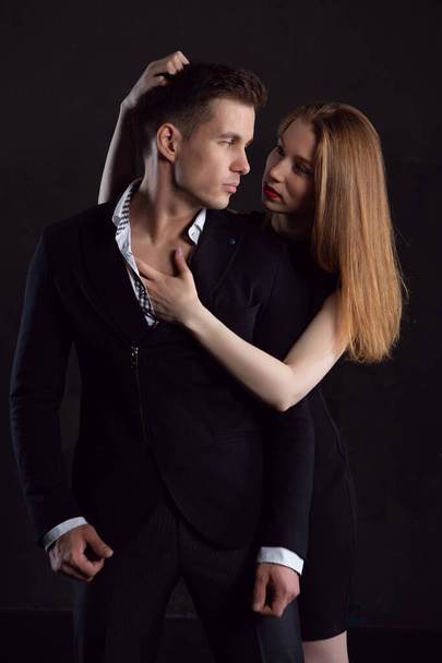 A sexy girl during a passionate embrace clutches her man's hair with one hand and touches his pumped up chest with the other - Фото, зображення