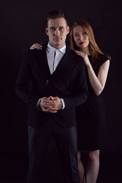 A beautiful sexy gently embracing couple on a black isolated background looks at the camera - Foto, Imagen