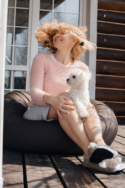 attractive woman with dog sitting on patio - Фото, изображение