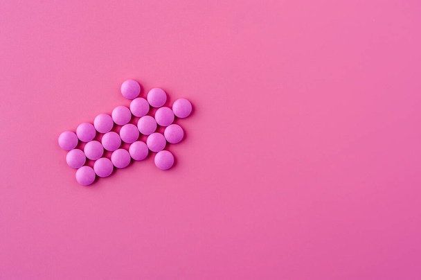 Close-up of pink pills lie on a pink surface - Фото, изображение