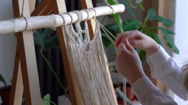 Fica em casa. trabalho durante a quarentena - uma menina na sala de estar tecelagem mural das cordas na técnica macrame
 - Filmagem, Vídeo