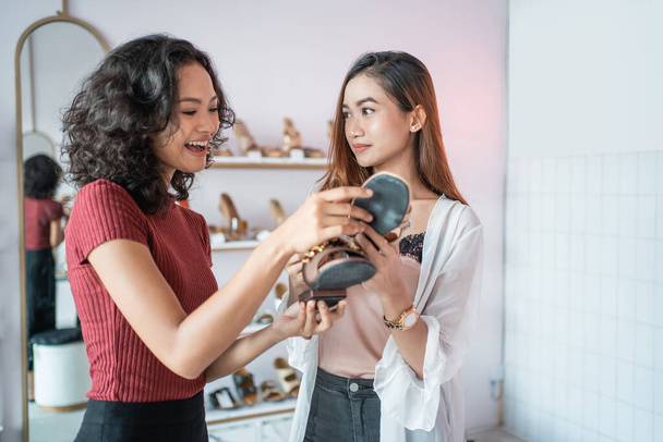 ブティックファッション店で靴を選ぶ女性と友人 - 写真・画像