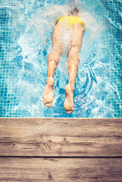 Boldog gyerek, aki jól érzi magát a nyári szünetben. A srác beugrik a medencébe. Aktív egészséges életmód koncepció. Tavaszi szünet! - Fotó, kép