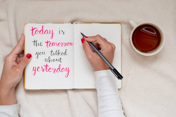 Κορίτσι χέρι γράφοντας ένα εμπνευσμένο και ενθαρρυντικό απόσπασμα: "Σήμερα είναι το αύριο για το οποίο μιλήσατε χθες". Επίπεδη προοπτική - Φωτογραφία, εικόνα