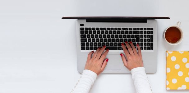 Mani femminili digitando sul computer portatile tastiera durante il telelavoro, banner con spazio di copia, per i blogger, affari. Vista dall'alto, piatta
 - Foto, immagini