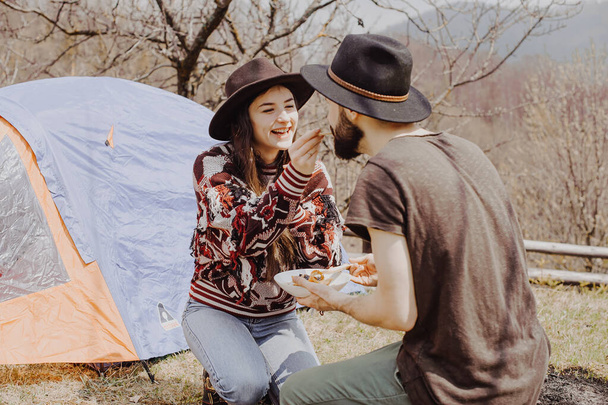 stylish young couple of travelers. Family on a walk in the mountains laid out a tent, prepare breakfast and plan a further itinerary - Foto, Imagem