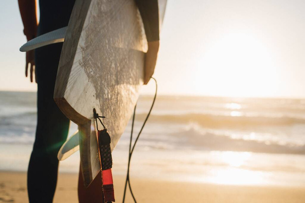 A closeup shot of a person holding a surfing board at the beach in Portugal - Fotó, kép