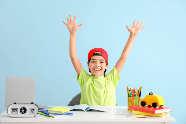 Happy little boy doing homework against color background - Photo, Image