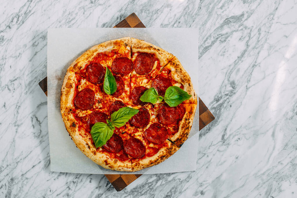 Italian pizza with mozzarella cheese and basil on a marble table - Photo, Image