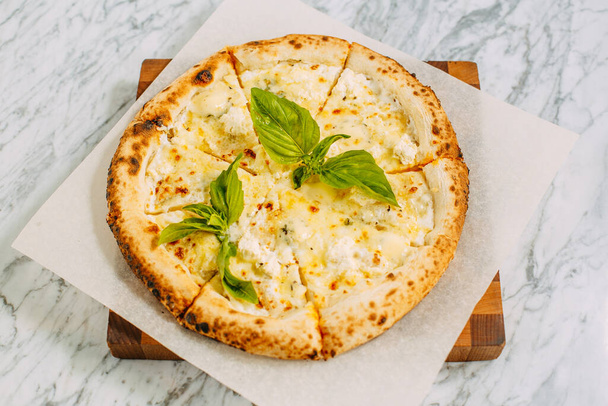 Italian pizza with mozzarella cheese and basil on a marble table - Φωτογραφία, εικόνα