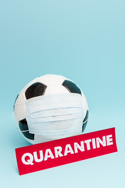 football in medical mask near paper with quarantine lettering on blue  - Photo, Image
