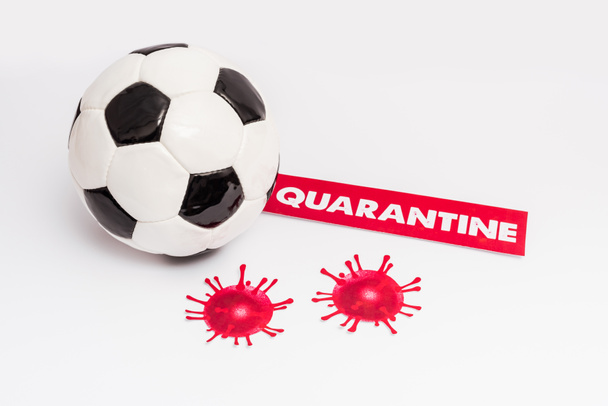 Fußball in Papiernähe mit Quarantäne-Schriftzug und gezeichnetem Virus auf weißem Grund - Foto, Bild