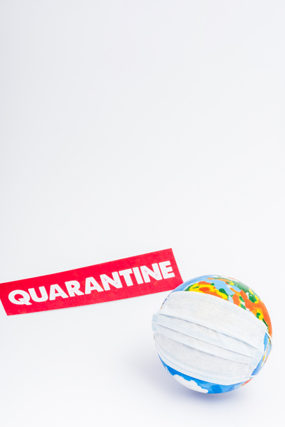 globe in medical mask near paper with quarantine lettering on white - Foto, Bild