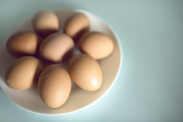 chicken eggs in a white plate on a blue background. Fresh produce from the village. Easter. Organic food - Foto, Imagen