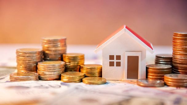 Real estate or property investment. Home mortgage loan rate. Saving money for retirement concept. Coin stack on international banknotes with house model on table. Business growth background - Photo, Image