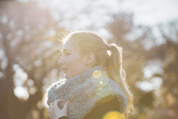 Güneş ışığı parkında nazik bir ifadeyle genç beyaz bir kadın. - Fotoğraf, Görsel