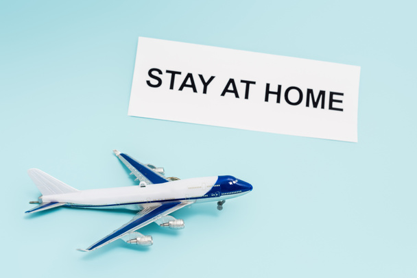 toy plane near paper with stay at home lettering on blue  - Foto, imagen
