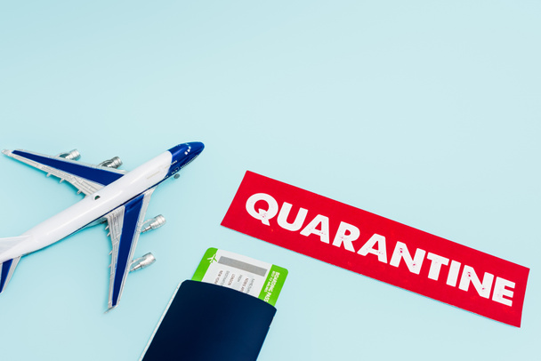 speelgoed vliegtuig in de buurt van papier met quarantaine, paspoort en vliegticket geïsoleerd op blauw  - Foto, afbeelding