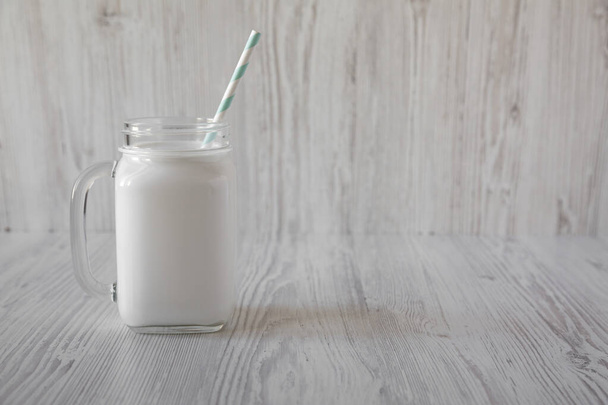 Kokosové mléko ve sklenici na bílém dřevěném pozadí, boční pohled. Kopírovat prostor. - Fotografie, Obrázek