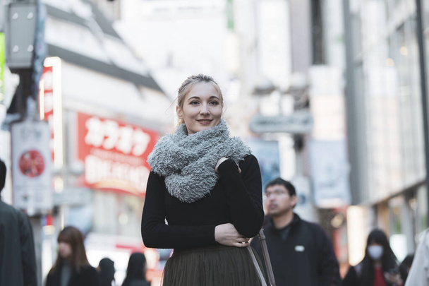 Young European woman sightseeing downtown Shibuya (Tokyo, Japan) with a smile - Photo, Image
