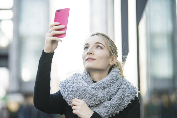 Mujer joven usando smartphone y tomando fotos y usando aplicaciones
 - Foto, Imagen