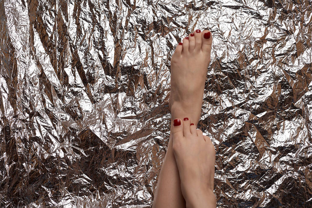 Los pies hermosos femeninos sobre el fondo hermoso en forma de la laminilla. Foto de moda de las piernas femeninas. Pedicura roja
. - Foto, imagen