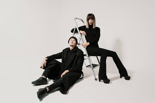 Fashionable man and woman sitting on a stair - Фото, зображення