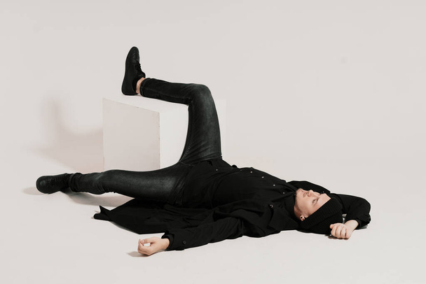 Fashionable man lying on white background with a leg on a cube - Foto, afbeelding