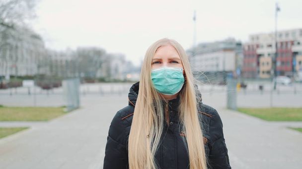 Пандемия коронавируса: блондинка в медицинской маске идет по улице
 - Фото, изображение