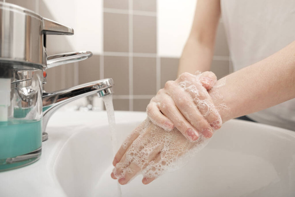 Kézmosás szappannal a csapvíz alatt a koronavírus megelőzésére, higiénia, hogy ne terjedjen tovább a koronavírus. Higiéniai koncepció, higiéniai higiénia, tisztaság, mosás, fertőtlenítés.  - Fotó, kép