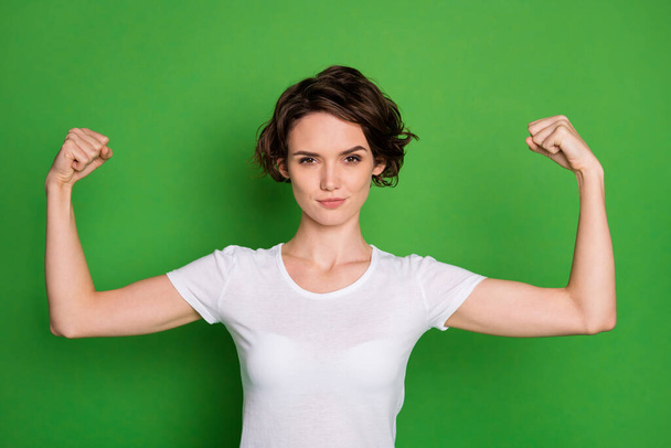 Photo of attractive self-confident lady wavy bobbed hairdo demonstrating two perfect shape biceps can beat any guy wear casual white t-shirt isolated bright green color background - Zdjęcie, obraz