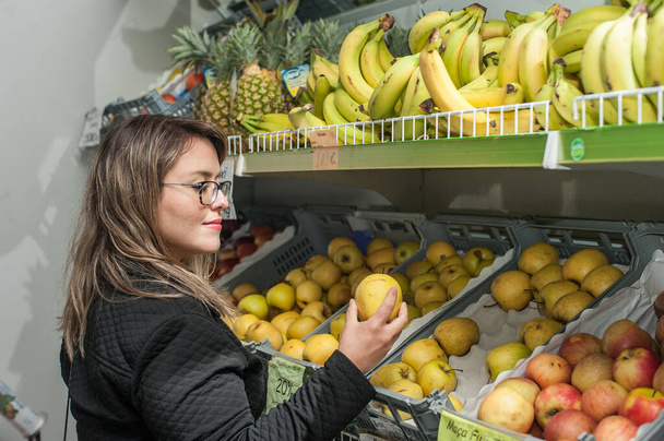 jeune femme blonde choisir des fruits dans une épicerie
. - Photo, image