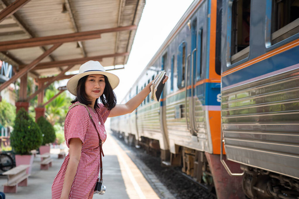 Ασιάτισσες τουρίστριες μεταφέρουν μια φωτογραφική μηχανή και χαμογελώντας έντονα στο σιδηροδρομικό σταθμό. - Φωτογραφία, εικόνα