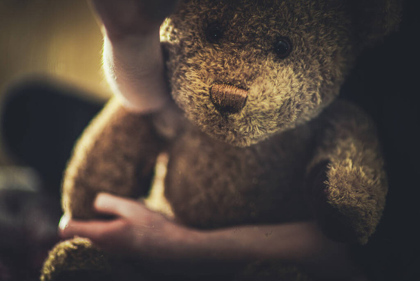 Nahaufnahme eines Kindes, das Teddybär auf dem Schoß hält.  - Foto, Bild
