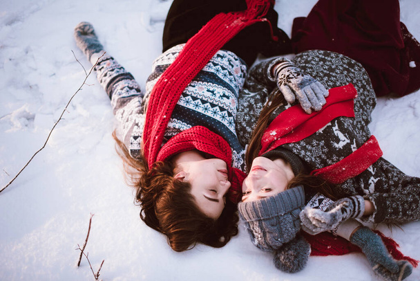 Two young teenage hipster girl friends together.Close up fashion portrait of two sisters hugs and having fun winter time,wearing sweater,best friends couple outdoors, snowy weather - Foto, imagen