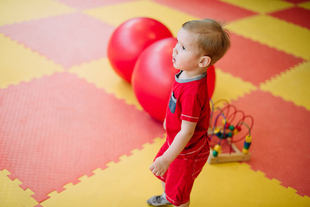 Šťastný rozesmátý chlapec 1-2 roky se baví v míčové jámě na narozeninové párty v dětském zábavním parku a v krytém herně. Dítě hrající si s barevnými míčky v dětském bazénu. Aktivity hračky pro malé dítě. - Fotografie, Obrázek