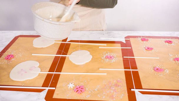 Versare zucchero caramellato su tappetini in silicone per fare lecca-lecca fatti in casa. - Foto, immagini