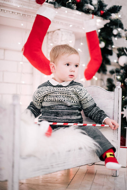 Kerst portret van een jonge jongen gezellige sfeer rond de open haard en kerstboom - Foto, afbeelding