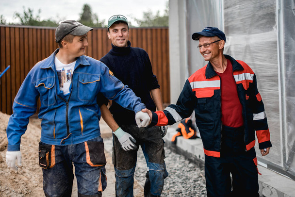 бизнес, строительство, командная работа и концепция людей - группа улыбающихся строителей под открытым небом
 - Фото, изображение