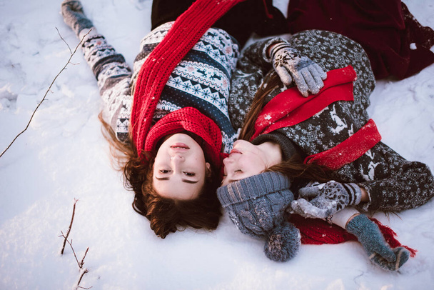 Two young teenage hipster girl friends together.Close up fashion portrait of two sisters hugs and having fun winter time,wearing sweater,best friends couple outdoors, snowy weather - Фото, изображение
