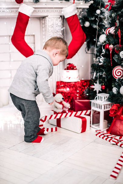 Χριστουγεννιάτικο πορτρέτο ενός νεαρού αγοριού ζεστή ατμόσφαιρα γύρω από το τζάκι και το χριστουγεννιάτικο δέντρο - Φωτογραφία, εικόνα