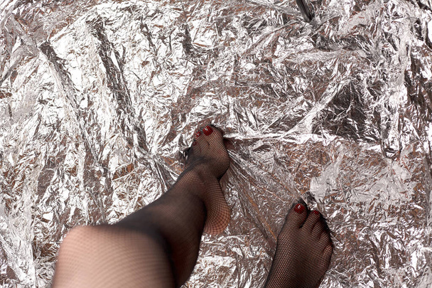 Όμορφα γυναικεία πόδια με δικτυωτό καλσόν. Στοκ-μοντέρνο μαύρο πλέγμα καλσόν και σέξι πόδια ενός νεαρού κοριτσιού. - Φωτογραφία, εικόνα