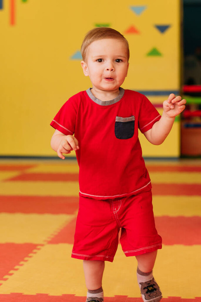 Szczęśliwy chłopak śmiejący się 1-2 lat bawiący się w balu na przyjęciu urodzinowym w parku rozrywki dla dzieci i krytym centrum zabaw. Dziecko bawiące się kolorowymi kulkami w basenie piłki plac zabaw. Zabawki do ćwiczeń dla małego dziecka. - Zdjęcie, obraz