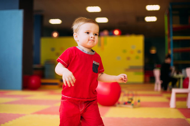 Boldog nevető fiú 1-2 éves szórakozás labda gödörben születésnapi party gyerekeknek vidámpark és beltéri játszóközpont. A gyerek színes labdákkal játszik a játszótéri labdarúgó medencében. Tevékenységi játékok kisgyereknek. - Fotó, kép