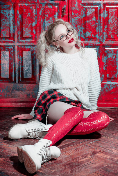 Foto de moda de una chica rubia con ropa de juventud moderna. Universidad, estilo escolar. Hipster chica usando gafas por una pared de ladrillo. Moda juvenil
 - Foto, Imagen