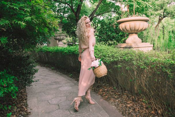 Sensuelle jeune blonde belle femme mignonne et élégante portant rose assis sur le rocher et regardant dans la caméra sur fond de palmier jungle verte tropicale en Chine
. - Photo, image