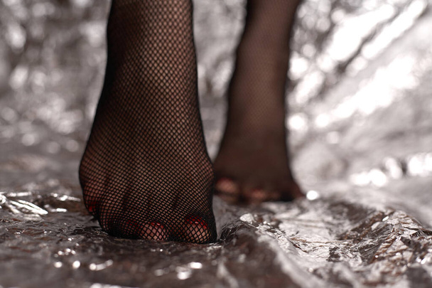 Mooie vrouwelijke voetjes in gaas panty. Stockfoto modieuze zwarte gaas panty en sexy voeten van een jong meisje. - Foto, afbeelding