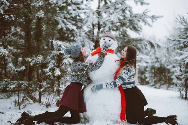 Two young teenage hipster girl friends together.Close up fashion portrait of two sisters hugs and having fun winter time,wearing sweater,best friends couple outdoors, snowy weather - Foto, Imagem